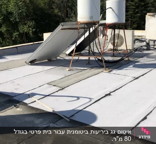 גג עם יריעות איטום לבנות ומיכלי מים